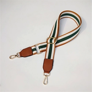 Detail of adjustable striped canvas strap with brown leather ends and gold metal hooks