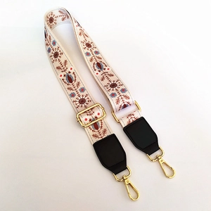 Close-up of floral embroidery strap with golden metal buckles and black leather ends