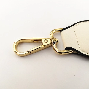 Detail of adjustable off-white leather strap with golden lobster clasp and stitching
