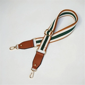 Adjustable green and white striped bag strap with brown leather ends and gold metal hooks