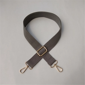 Detail of adjustable grey cotton shoulder strap with polished gold-tone metal buckles