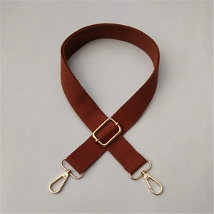 Detail of adjustable brown woven cotton bag strap with gold lobster clasps and buckle