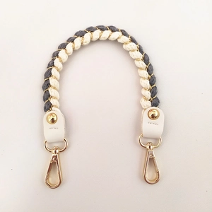 Detail of woven white and grey bag handle strap with gold hardware and leather ends