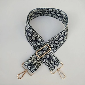Detail of adjustable snakeskin pattern bag strap with gold-tone rotating metal buckles