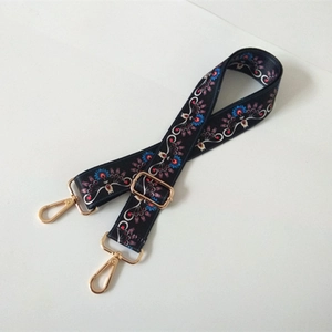 Close-up of ethnic floral wide strap with golden metal lobster clasps and buckles