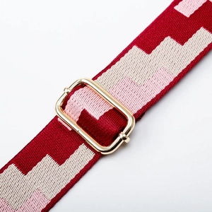 Macro detail of red and pink geometric weave strap with gold adjustable buckle