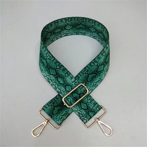 Detail of green snake skin pattern wide bag strap with luxury gold metal hardware and buckle