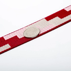 Close-up of geometric woven pattern bag strap in deep red and beige colors