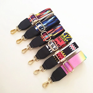 Detailed view of colorful wide handbag straps with ethnic patterns and gold metal buckles