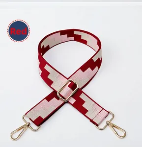 Close-up of a wide adjustable fabric bag strap with red geometric pattern and gold clasps