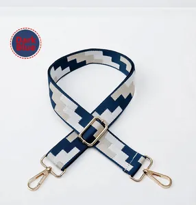 Detail of adjustable deep blue geometric woven strap with golden metal swivel hooks