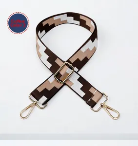 Detail of adjustable woven bag strap with coffee geometric pattern and gold buckles