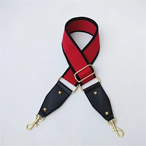 Close-up of red and black adjustable bag strap with gold metal hooks and rivets
