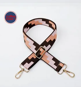Detail view of woven brown geometric wide shoulder strap with gold metal buckles