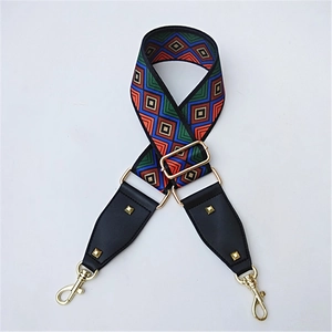 Close-up of wide geometric pattern bag strap with golden metal lobster clasps and rivets