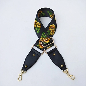 Detail of adjustable sunflower patterned bag strap with golden rivets and hardware