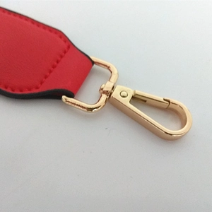 Detail of red leather bag strap with polished gold lobster clasp and fine stitching