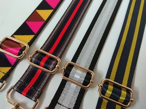 Detail of four colorful patterned fabric handbag straps with gold metal hardware