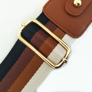 Detail of adjustable striped bag strap with gold metal buckle and leather ends