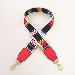 Close-up of ethnic geometric pattern strap with red leather ends and gold metal hooks