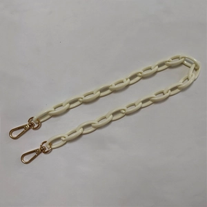 Macro detail of cream acrylic thick chain strap with gold metal lobster clasps