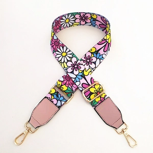 Detailed view of colorful floral printed bag strap with gold metal hooks and pink leather trim