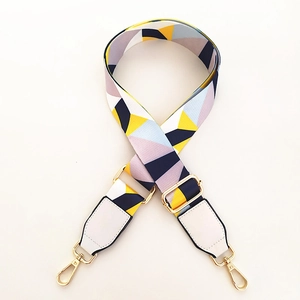 Close-up of colorful geometric ethnic style bag strap with gold metal hooks and white leather