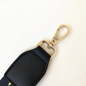 Detail of adjustable bag strap with gold lobster clasp and black lychee leather connector