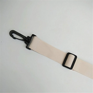 Detail of off-white woven shoulder strap with black swivel hooks and adjustable buckle
