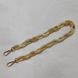 Macro detail of amber resin bag chain with polished gold metal lobster clasps