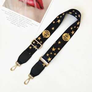 Detail of adjustable black and gold bag strap featuring star patterns and metal clips