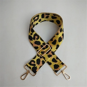 Close-up of leopard print bag strap with golden metal hooks and adjustable buckle