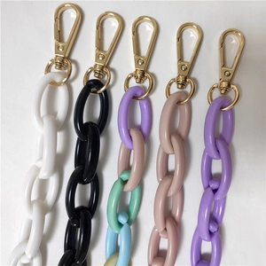 Detail of acrylic handbag chain straps with chunky oval links and gold metal lobster clasps