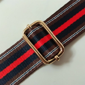 Macro detail of adjustable nylon bag strap with colorful stripes and gold metal buckle