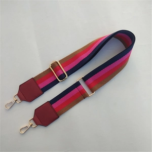 Adjustable striped fabric bag strap with burgundy leather ends and gold metal buckles