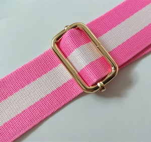 Detail of pink and white striped woven bag strap with polished gold metal buckle