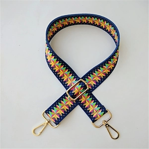 Close-up of colorful geometric star pattern on adjustable woven bag strap with gold metal hooks