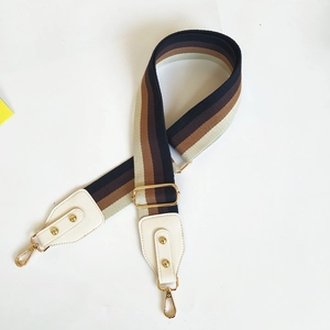 Detailed view of adjustable striped purse strap with gold lobster clasps and beige leather ends