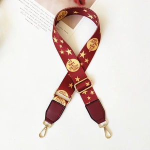 Detail of adjustable wine red woven strap with gold star print and metal swivel hooks