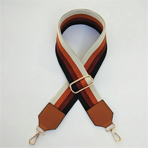 Detail of wide striped bag strap with gold lobster clasps and brown leather ends
