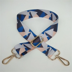 Detail of adjustable wide bag strap with geometric pattern and gold metal hooks