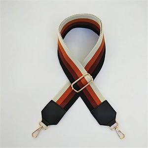 Detail of adjustable striped canvas bag strap with faux leather ends and gold metal clips