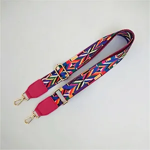 Detail of colorful geometric woven shoulder strap with gold metal hooks and pink leather end