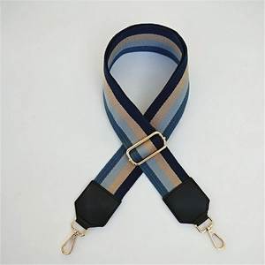 Detail of adjustable striped nylon strap with gold metal buckles and black leather ends