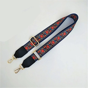 Detailed close-up of ethnic style embroidered bag strap with golden lobster clasp and buckles