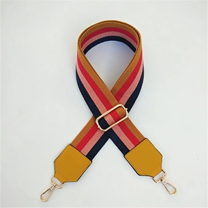 Close-up of adjustable striped woven strap with gold metal buckles and yellow leather ends