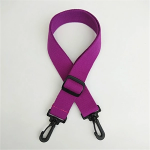 Detail of purple canvas bag strap featuring black plastic buckle and swivel hooks