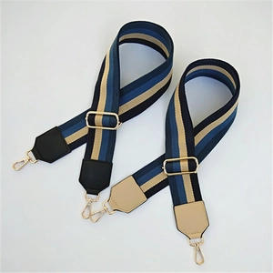 Detail of striped woven shoulder straps with golden metal hooks and leather reinforcements