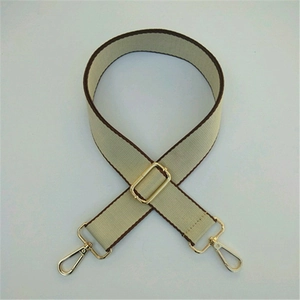 Adjustable beige woven shoulder strap with dark brown trim and gold metal buckles