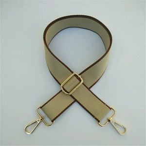 Detail of adjustable beige and brown canvas strap with golden metal hooks and buckles